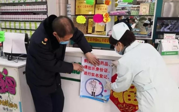 赤峰市紅山區市場監管局監管人員正在藥店張貼“實名登記購買退燒藥”宣傳海報。（赤峰市市場監管局供圖）