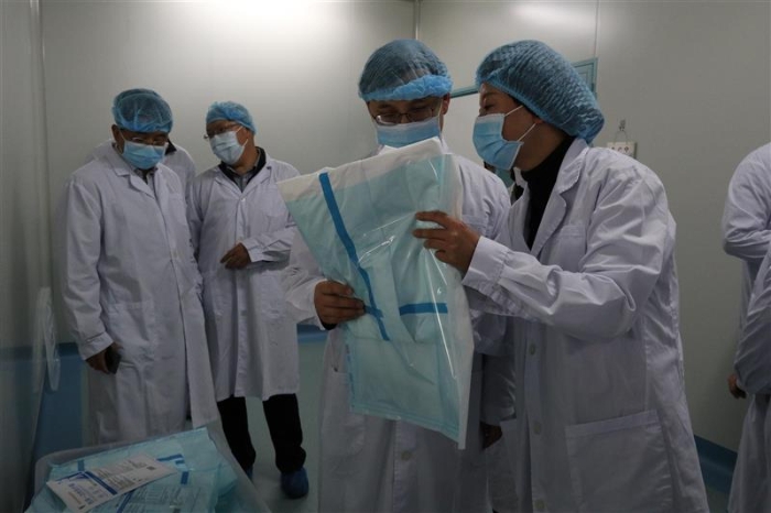 圖為云南省藥監局黨組書記、局長劉本軍（右二）檢查該企業生產的醫用一次性防護服。（云南省藥監局供圖）