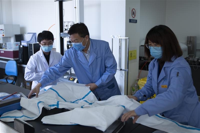 圖為趙玉杰（中）檢查醫(yī)用防護服應急檢測工作。