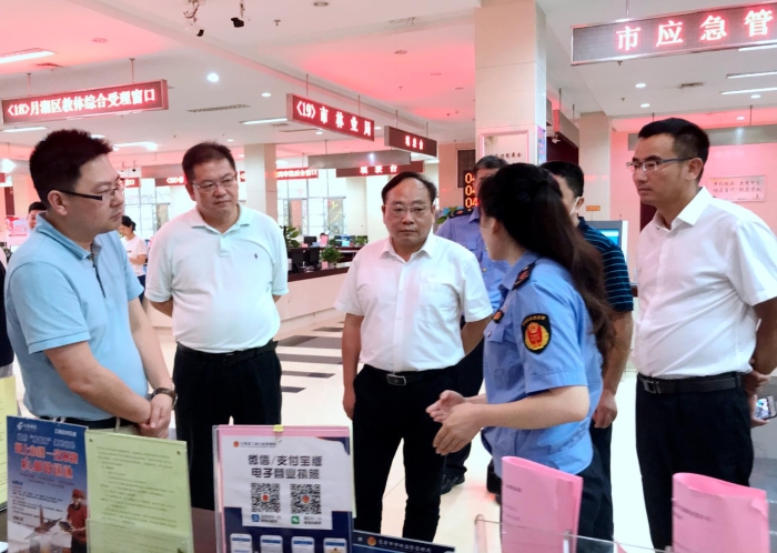 上官新晨（左三）在鷹潭市行政服務中心詳細了解“一照含證”改革情況。
