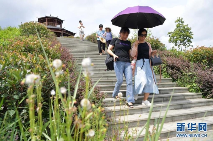 游客在江西省尋烏縣文峰鄉上甲村附近的生態修復區觀光游玩（7月19日攝）。從前這里是大面積的廢棄稀土礦山。目前除了恢復植被，當地還搭建了觀景平臺，修復區成為了周邊游客觀光休閑的好去處。  新華社記者 彭昭之 攝