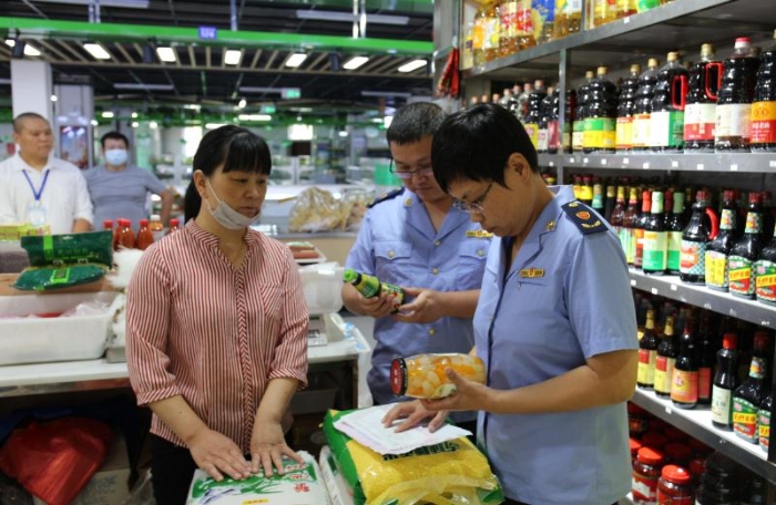 圖為執法人員檢查農貿市場內商超在售食品。