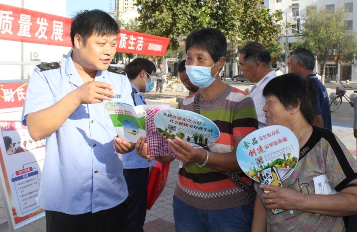 圖為執(zhí)法人員向群眾宣講食品安全知識。