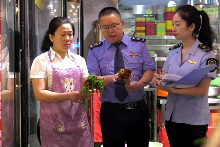 圖為執(zhí)法人員在一火鍋店檢查火鍋食品原輔材料進(jìn)貨情況。