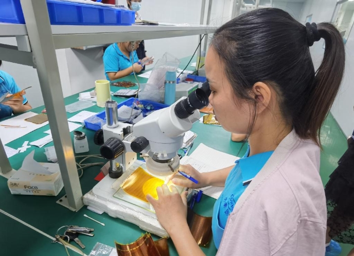 開蒙醫療員工在用顯微鏡檢查人體成分分析儀芯片上的箔片集成電路是否有缺陷。