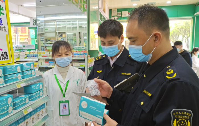 圖為執法人員在一藥店查看抗原檢測試劑材料。