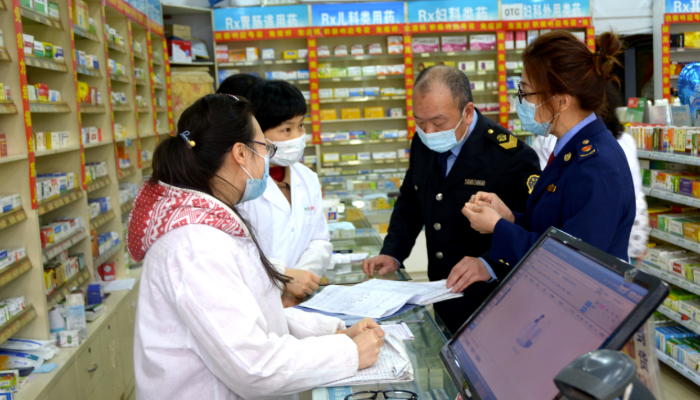 圖為執(zhí)法人員在一家藥店檢查防疫物資銷售記錄。