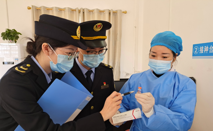 圖為執法人員在一家醫院檢查新冠疫苗和抗原檢測試劑。