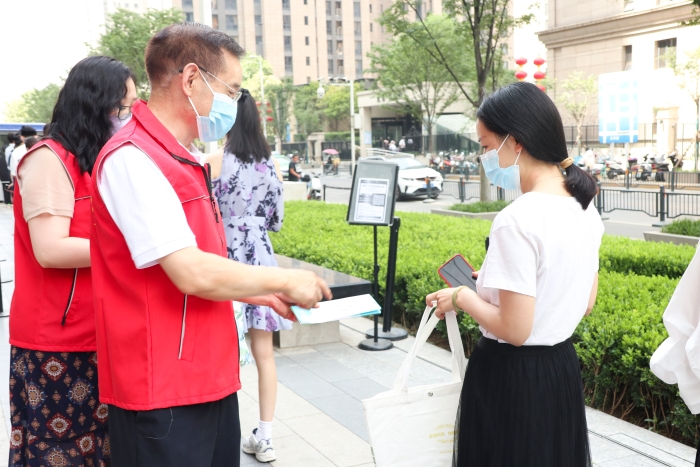 圖為藥監系統志愿者為排隊等待檢測的居民發放科普抗疫小禮包，并為居民開展藥品安全科普，耐心解答居民用藥、用械安全方面的疑問和咨詢。（郝曉靜攝）