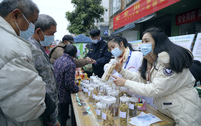 圖為工作人員現(xiàn)場向群眾講解常用中藥材的鑒別知識，普及藥品安全相關法律法規(guī)。
