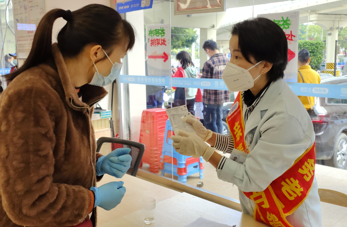圖為執業藥師對前來領取拆零袋裝布洛芬的群眾仔細說明用藥注意事項。