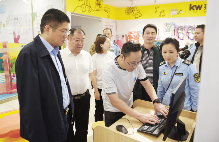 圖為湖南省藥監局副局長覃永忠（左一）查看化妝品經營戶產品質量臺賬。