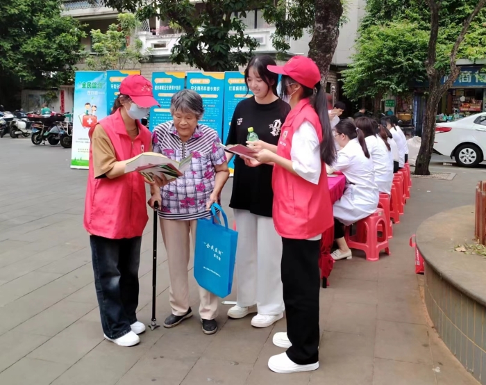 圖為工作人員向過(guò)往居民發(fā)放“全民監(jiān)測(cè)”科普宣傳資料。